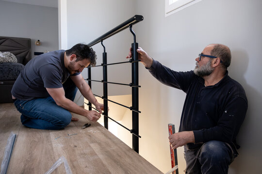 Men installing a black metal safety handrail for home renovation or construction project