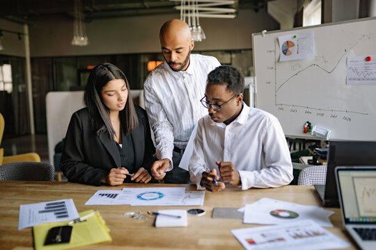 A diverse team collaborates on a project in a modern office space while analyzing graphs and data during a brainstorming session