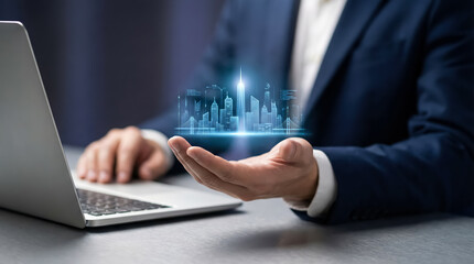 Fototapeta premium Businessman holding a digital hologram of a futuristic city above his hand next to a laptop, symbolizing technology and innovation