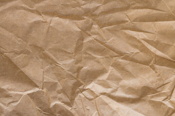 Obraz premium Crumpled Brown Kraft Paper Texture Background,Top view of creased and crumpled brown kraft paper texture. Abstract background of wrinkled recycled paper sheet with organic folds and shadows.