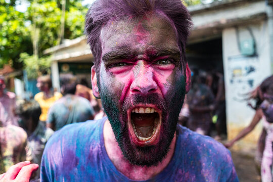 Fully excited traveler shouting during Holi festival surrounded by a festive crowd
