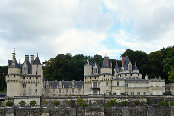 Obraz premium View of the Château d'Ussé rising above the river with a stone bridge in the foreground. Elegant French architectural landmark featuring historic towers, fortified walls, and landscape
