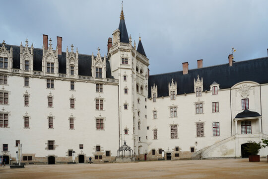 View of the inner courtyard of the Ch&acirc;teau des ducs de Bretagne in Nantes, France. The white tuffeau stone facade features Gothic and Renaissance architectural details under a neutral overcast sky
