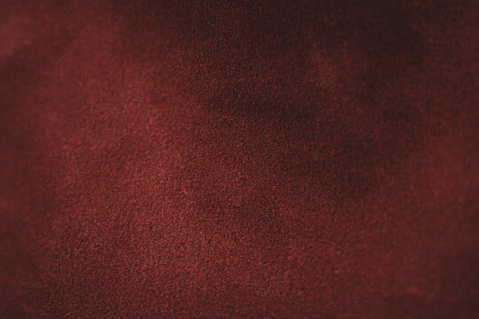 Macro photography of deep burgundy split leather with uneven moody lighting, offering an elegant napped texture for luxury backgrounds.