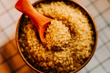Bulgur groats in a bowl with a wooden spoon on a checkered tablecloth