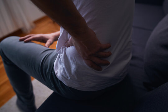 Man with hip, back, spine and sciatica pain at home.