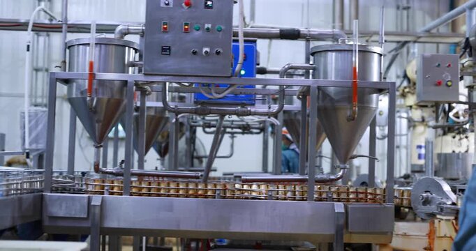 Food manufacturing industry. Worker working in canned food factory. Food industry. Canned fish factory. Worker's hand holding sardine to cutting head. Worker in food processing production line. 