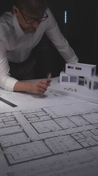 Architect designing modern building plan, creating scale model and blueprint for design and construction project. Concept of architecture and business in low key lighting