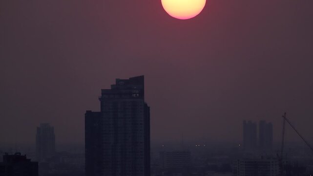 Time-lapse of the sun setting over a capital city skyline with buildings silhouetted against the sky