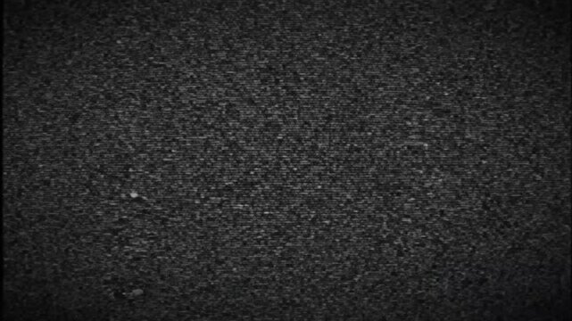 Monochromatic aerial view of two vehicles traversing a vast patterned crop field