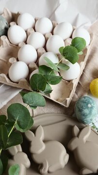 Eggs are placed on a table next to a dish shaped like bunnies and a towel with a green checkered pattern.