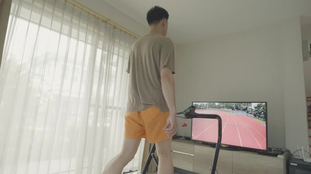 A person exercises on a treadmill indoors, engaged with a virtual running track displayed on a screen. The setting highlights a blend of fitness and technology, providing an immersive workout experien