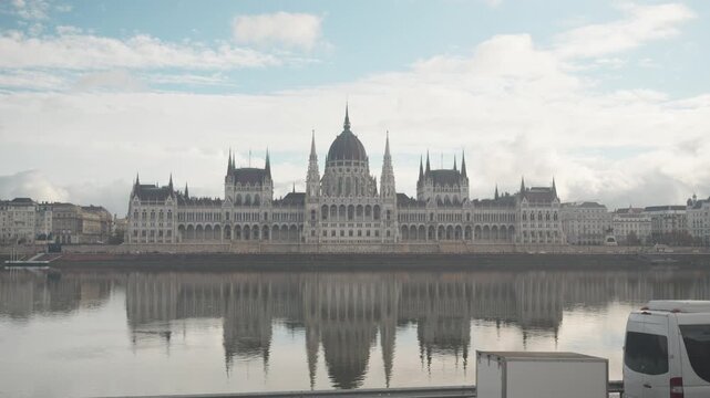 A stunning view of a historic parliament building with intricate architecture, reflecting beautifully in the still waters below. The surrounding landscape enhances the serene atmosphere, making it a p