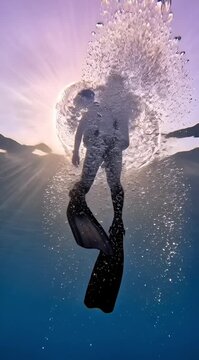 Scuba diver swimming upward toward sunlight in clear blue ocean