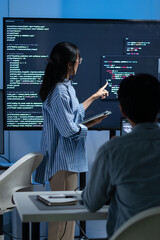 Asian Female Developer presenting code to Colleagues or Team Explaining code and discussing on software development task during code meeting or software training, Cybersecurity in office at night. © SAT65