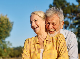 Happy active senior couple having fun talking and hugging in park outdoors