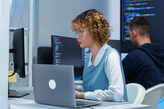Software Engineer, AI Programmer Software Developing, Focused Female Computer Programmer working on Computer Writing Code, Developing software application looking at Screen in Tech Office at night.