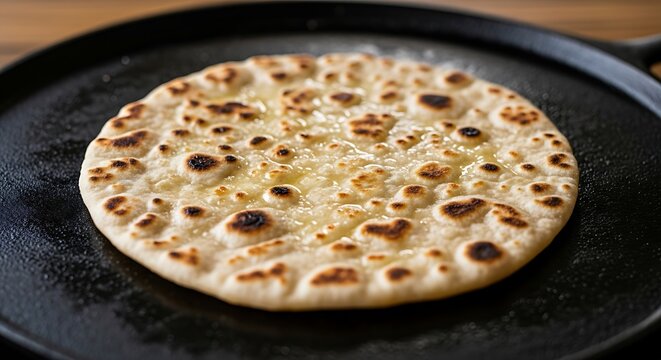 Golden flatbread glistens with melted butter on a hot griddle.