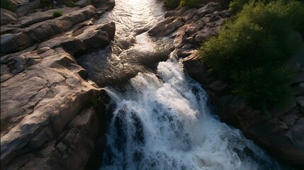 Aerial view of a powerful waterfall cascading over textured rocks during the golden hour