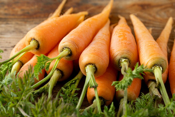 新鮮な葉付きにんじん(木目背景)