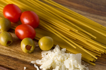 Closeup of Spaghetti Pasta, Green Olives and Parmesan Cheese on a Wooden Counter