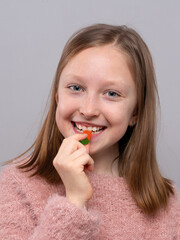 Teen girl holding blue gummy candy above her mouth in studio, sweet snack craving, candy treat, playful lifestyle, sugary temptation