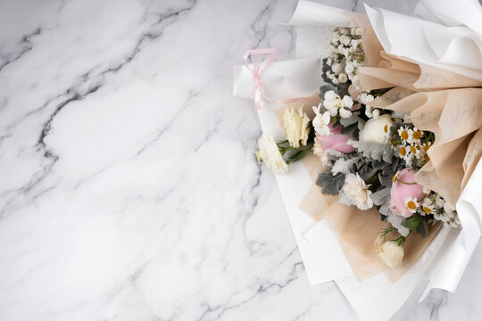 Pastel colored flower bouquet on marble background with copy space