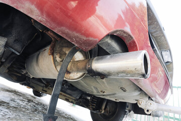 Car exhaust pipe with visible emissions in winter. Vehicle muffler releasing fumes under rear...