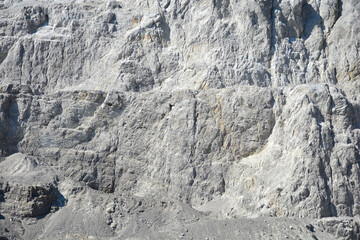 A close up view of a steep stone quarry face showing intricate rocky layers and rough textures of...