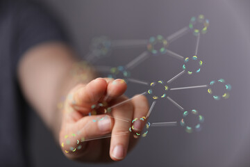 Abstract image of a human hand touching a futuristic network of connections, representing...