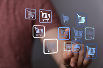 Fototapeta premium Close-up of a hand interacting with shopping cart icons, representing online shopping, ecommerce, and digital retail. Concept of buying, commer