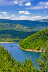 Fototapeta premium Panoramic landscape of Lake Zavoj surrounded by forested hills and mountains near Pirot in southeastern Serbia under blue sky
