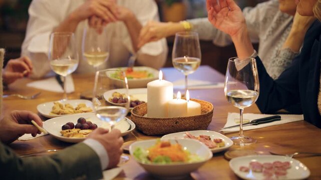 Group of elegant senior friends dining and socializing together. Mature people enjoy appetizers and wine during a cozy evening at home