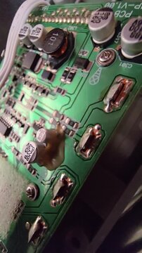 Macro steady shot of a high-quality electronic circuit board focusing on a copper wire inductor coil and electrolytic capacitors on a green PCB.