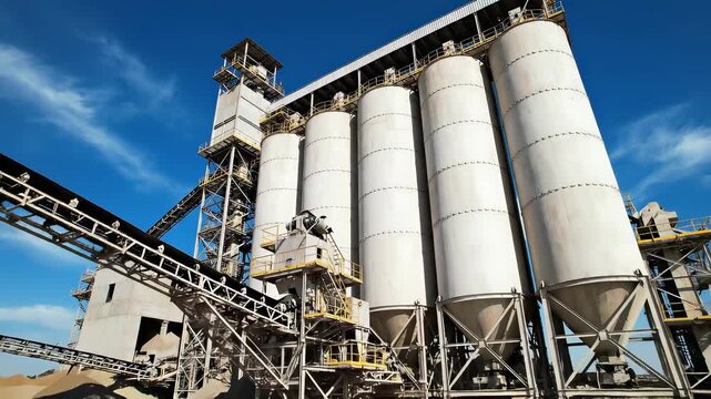 Industrial cement and aggregate processing plant with large silos and conveyor belts