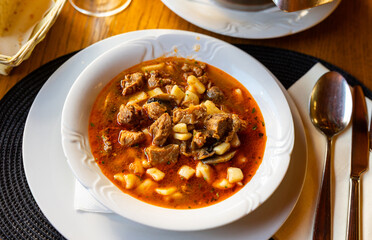 On table there is pot with ladle filled with thick meat stew kobanak - traditional Croatian food in...