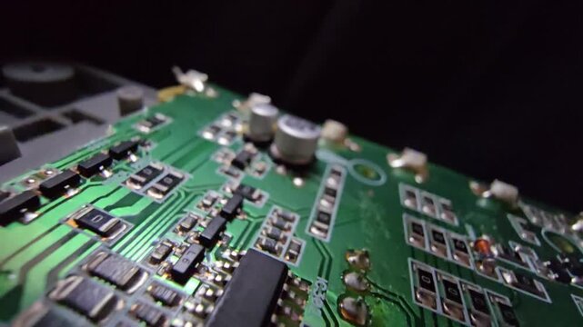 Macro steady shot of a high-quality electronic circuit board focusing on a copper wire inductor coil and electrolytic capacitors on a green PCB.