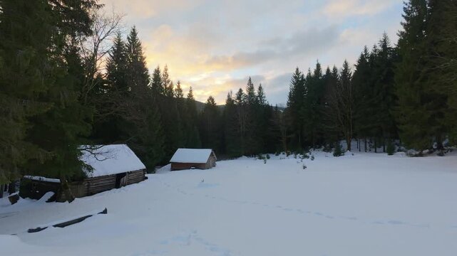 Rustic Huts in Snowy Carpathian Forest at Sunset