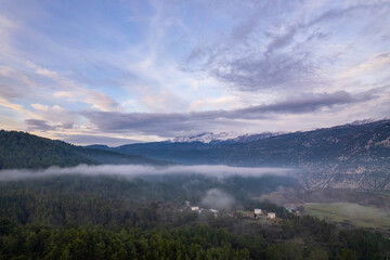 Obraz premium A stunning drone perspective of Çaltepe village on the St Paul Trail, showcasing the harmony between traditional rural life, green agricultural fields, and the dense pine forests covering the rugged s