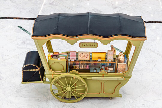 5 December 2025, Abu Dhabi, UAE: Laduree sweet cart displaying colorful macarons and other pastries for sale, a mobile luxury dessert boutique