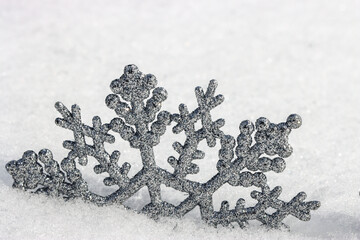 Shiny, silver snowflake ornament set into a snowbank.