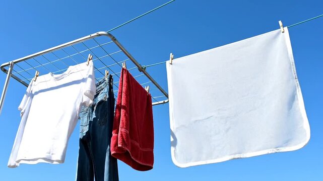 Laundry drying on clothesline and rack under blue sky