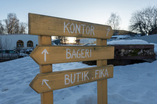 Trosa, Sweden A wooden outdoor sign says Office, bakery and boutique and fika in Swedish.
