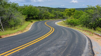 Naklejka premium Winding asphalt road with double yellow lines through lush green trees and shrubs under a cloudy sky