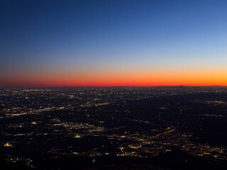 Naklejka premium Vista aerea notturna della città con luci urbane sotto cielo blu scuro.