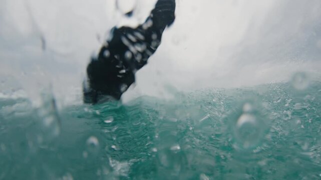 Surfer rides the wave and does sharp turn. In water footage of the rider surfing the wave