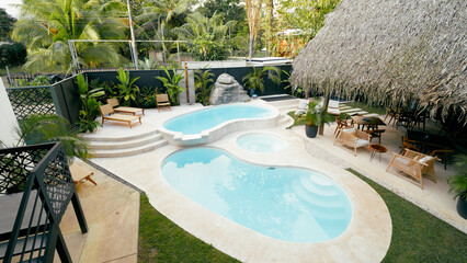Luxury resort backyard presenting a swimming pool complex with relaxing lounge areas and various...