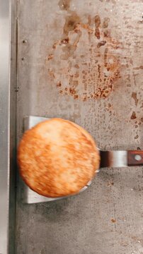 Chef cooking arepas and meat on a griddle