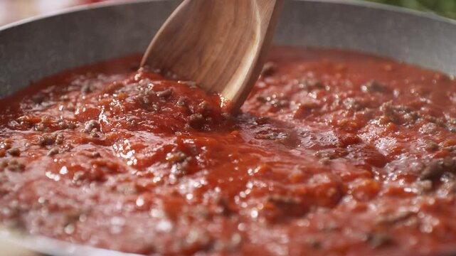 Stirring Tomato Sauce with Minced Meat Using an Olive Wood Spoon - Skillet Filled with Thick Bubbling Sauce for Spaghetti Bolognese, Dolly out
