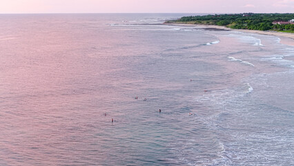Obraz premium Avellanas Beach, Costa Rica, showing surfers waiting for ocean waves during a pastel colored sunset from an aerial view